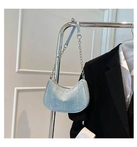 Detail of light blue glitter shoulder bag with silver chain strap on metal rack
