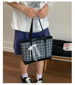 Detail of checkered tote bag with lace bow, pearl pendant and leather handles