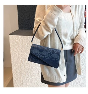 Detailed view of blue snake-patterned leather texture and gold hardware on small tote bag