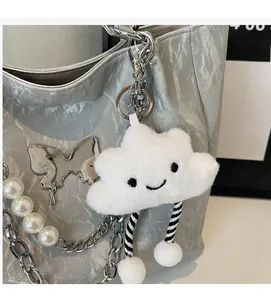 Dettaglio del ciondolo a nuvola in peluche bianco con ricamo su borsa argento lucido