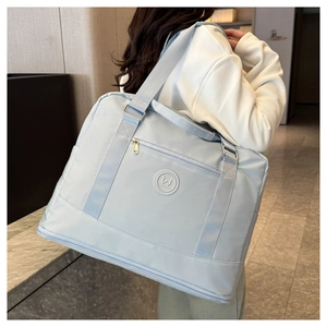 Detail of light blue waterproof oxford travel bag showing shoe compartment and logo