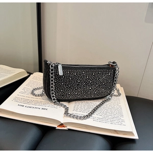 Detail of black rhinestone evening bag with silver chain strap on a vintage book