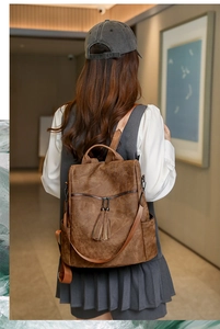 Close-up of dark brown vintage matte leather backpack featuring decorative tassels