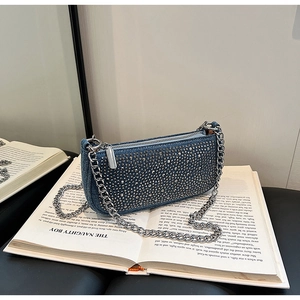Close-up of blue denim chain bag featuring silver studs and metallic hardware