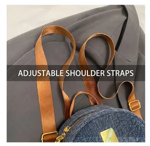 Dettaglio degli spallacci regolabili in nylon marrone e fibbie dorate sullo zaino denim