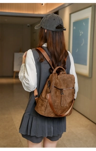 Close-up of vintage brown backpack featuring decorative long tassels and metal zipper details