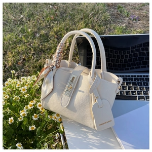 Détail du sac seau en cuir grainé crème avec poignée en foulard et fermoir métallique