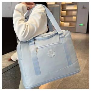Detail of light blue travel bag with wide shoulder strap and spacious compartments