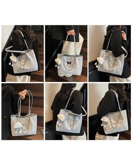 Detail view of large light blue tote bag with chain, pearls, and cloud charm decoration