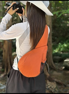 Detail of orange oxford crossbody chest bag with black mesh side pocket for hiking