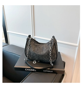 Close-up of crescent denim shoulder bag with silver rhinestones and chain strap detail