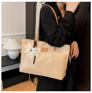 Detailed shot of beige tote bag with floral pendant and minimalist PU leather texture