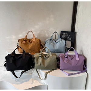 Selection of colorful travel duffle bags in nylon fabric displayed on minimalist platforms