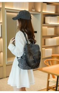 Close-up of vintage grey backpack with tassel zippers and soft matte texture detail