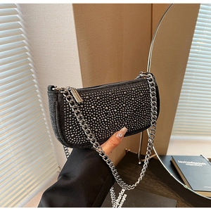 Close-up of black denim baguette bag featuring silver studs and chunky metal chain