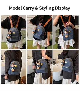 Dettaglio zaino in denim blu con spalline marroni e ciondolo a forma di orsetto