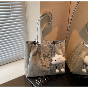 Close-up of silver-grey pleated tote bag with pearl chain and cloud plush charm detail