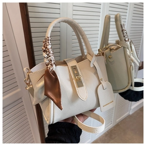 Détail du sac seau en cuir crème avec poignée en soie et fermoir tournant doré élégant