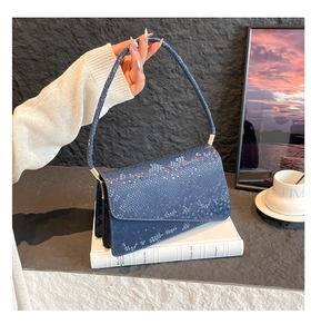 Detail showing blue snake-pattern texture on handbag with gold metallic buckle and strap