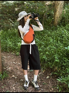 Outdoor leisure style featuring an orange nylon crossbody chest bag and casual hiking outfit