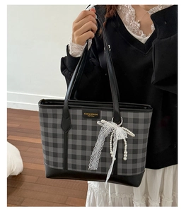 Detail of checkered tote bag with lace pearl bow charm and reinforced leather base