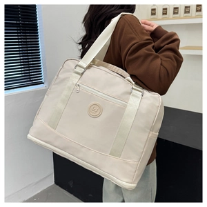 Rear view of a model carrying a beige oversized water-resistant travel tote bag
