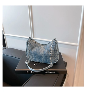 Close-up of light blue denim hobo bag with silver chain detail and leather strap