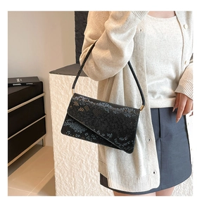 Close-up of black snakeskin embossed leather shoulder bag with elegant gold hardware