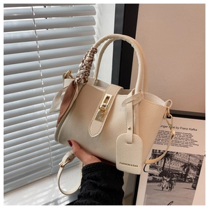 Détail du sac seau crème en cuir grainé avec poignée en foulard et fermoir doré
