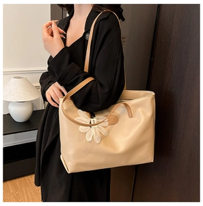 Detail of off-white tote bag with brown straps and a white fabric flower accessory