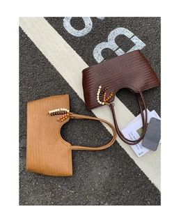 Close-up of woven tote bags in brown and tan with wooden bead tassel details