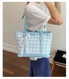 Detail of checkered tote bag with lace bow and pearl charm worn by a model