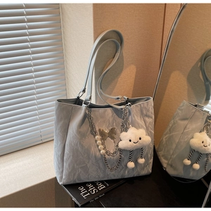 Detail of light blue tote bag with cloud texture, silver chain, and pearl charm