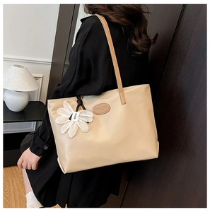 Detail of minimalist beige tote bag with daisy pendant and faux leather texture