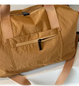Detail showing smooth zipper pocket and khaki nylon texture of the travel bag
