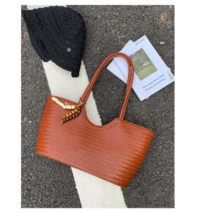 Detailed view of brown woven tote bag texture with decorative wooden bead charm