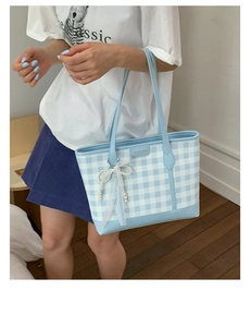 Detailed shot of blue plaid tote bag with pearl lace bow and fashion brand tag