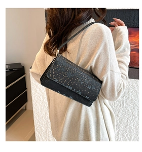 Detail view of a black snake pattern shoulder bag with flap design and slim leather strap