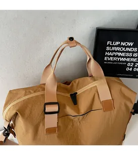 Detail of tan travel bag featuring reinforced leather patches and a woven handle strap