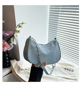 Detail showing light blue denim underarm bag with silver rhinestones and chain strap