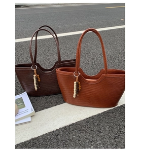 Close-up of woven tote bags in brown and caramel with wooden bead charms and handles