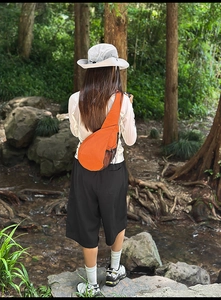 Outdoor model shot showing the orange crossbody sling bag fit and ergonomic design