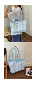 Detail of blue gingham tote bag with lace bow, pearl charm and leather logo plate