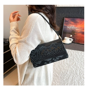 Close-up of black snake pattern shoulder bag shown from a side-view on a model
