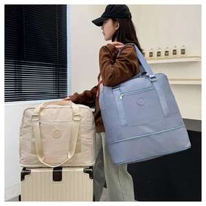 Detail of travel duffel bags in beige and blue showing expandable bottom and nylon texture