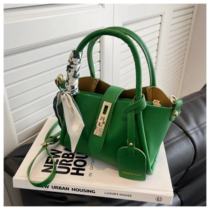 Détail d'un sac à main vert en cuir grainé avec fermoir doré et foulard en soie décoratif