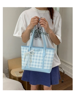 Detail of light blue checkered tote bag with lace pearl bow and leather handle