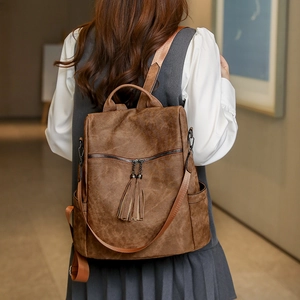 Detail of vintage brown PU leather backpack featuring tassel zippers and side pockets