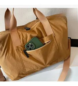 Detail of a large brown travel bag with a front zipper pocket and nylon texture