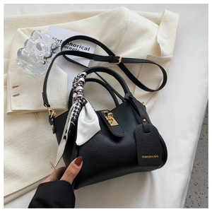 Détail du sac seau en cuir grainé noir avec foulard décoratif et fermoir doré chic